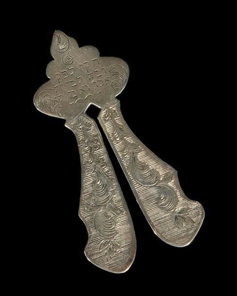 MAGUEN OU LYRE DE CIRCONCISION France, daté en hébreu 1750. Argent ciselé et gravé. Hauteur: 8,4 cm Poids: 23,9 g
Maguen en argent portant sur une face un décor de volutes feuillagées avec au sommet deux lions rampants supportant la lettre hébraïque[shin]. Sur l'autre face le texte hébraïque suivant: Année 510 du petit comput [1750] Mots-clés: Judaica, Jewish, Hebrew, Judaïsme, Hébreu.
Mogen or Circumcision Clamp. France, dated in Hebrew 1750. Chased/engraved silver.