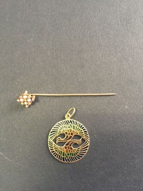 Pendentif en or jaune 18K, orné de deux paons émaillés plique-à-jour. On joint une petite épingle de cravate en or 18K sommée de petites perles. Poids brut total: 5,5 g