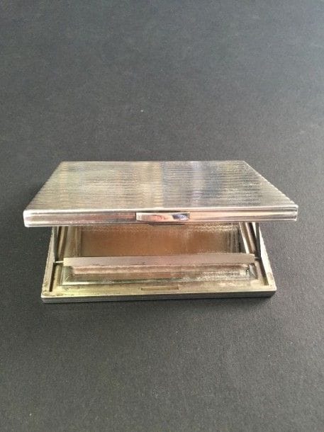 CARTIER
Poudrier en argent guilloché à motifs de godrons, il recèle un miroir biseauté. Signé et numéroté. Dans son écrin. Dimensions: 8,5 x 6,5 x 1 cm - Poids brut: 140,9 g (rayures)