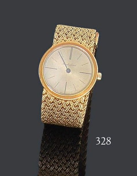 BUECHE GIROD
Montre de dame en or jaune 18K, cadran rond, fond satiné, index bâtons, bracelet en vannerie d'or, mouvement mécanique. Numérotée YG9901-2 69392. Longueur: 16,5 cm - Poids brut: 46,2 g (mouvement à réviser)