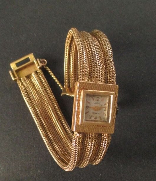 LUXIA
Montre de dame en or jaune 18K, cadran carré, bracelet en or jaune tressé, mouvement mécanique. Poids brut: 30 g (mouvement à réviser, remontoir métal)