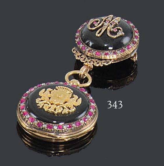 FÉLICIEN GROS
Montre de poche en or jaune 18K, cadran émaillé blanc, chiffres romains, le revers émaillé appliqué d'un blason en or dans une bordure soulignée de rubis alternés de diamants de taille ancienne, retenue par une broche en or jaune émaillée, appliquée du chiffre M serti de rubis et de diamants, dans un entourage de diamants et de rubis alternés. Poids brut: 41,8 g (mouvement à réviser, manque la lunette, soudures)