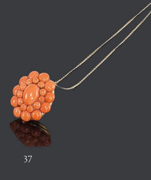 Pendentif porte-souvenir en or jaune 18K, orné d'un motif floral stylisé en pastilles de corail, coulissant sur une chaîne d'or jaune. Travail de la fin du XIXe siècle. Poids brut: 10,9 g (2 pastilles rapportées)