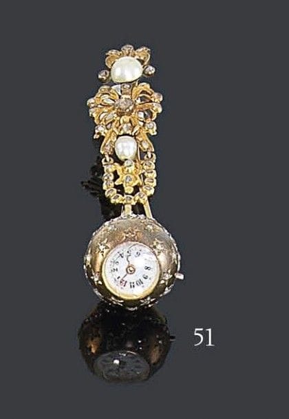 Montre-boule de Genève en or jaune 18K piquée et ceinturée de diamants taillés en roses, fond émaillé blanc, index peint chiffres arabes. Travail du XIXe siècle. Hauteur: 2 cm - Diamètre: 5,5 cm Poids brut: 14,9 g (mouvement à réviser, manque). On joint une spatule en vermeil, ajourée de rubans stylisés, sertie de deux demi-perles et de diamants taillés en roses. Travail du XVIIIe siècle, Espagne. Hauteur: 6 cm - Poids brut: 6 g