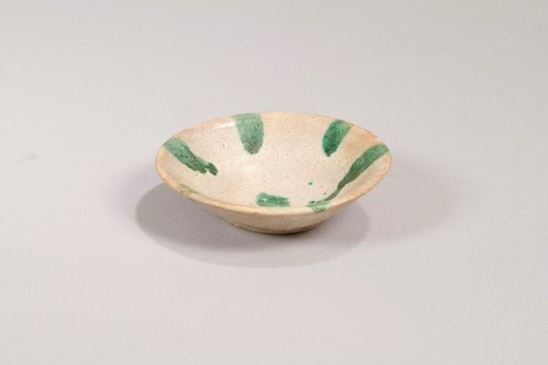 Coupelle en céramique, Iran, Nichapur, Xe siècle. 
En argile à glaçure crème et bandes rayonnantes vertes autour d'un point.
Diam.: 13 cm, Haut.: 3,5 cm 
État: restaurations
A Nishapur glazed pottery bowl, Iran,10th century 