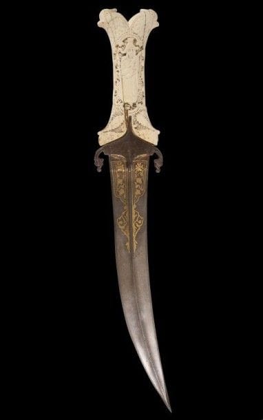 Rare poignard, jambiya, Iran qâjar, XIXe siècle.
Lame courbe à arête centrale damasquinée au talon de motifs floraux et quillon achevé en têtes de dragon. Poignée en os finement sculptée aux extrémités de deux têtes de perroquet et de deux masques animaliers coiffés de trois palmes enserrant sur chaque face un cartouche polylobé orné d'une femme debout tenant un instrument de musique et d'un roi assis sur un trône s'appuyant sur une épée. L'ensemble sur un fond de résille ou de guirlande florale.
Long.: 33 cm
A dagger, Jambia, Iran, Qâjâr, 19th century