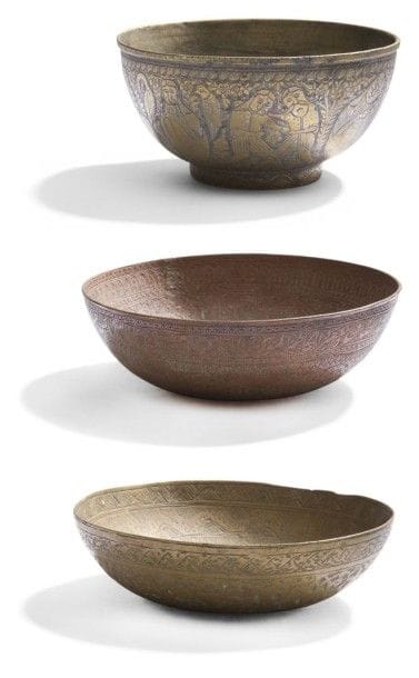 Trois coupes en cuivre et bronze, Iran, XIXe siècle.
L'une en cuivre à décor d'arabesques bordées d'une frise de cartouches inscrits des noms des imams et du prophète Mohammad ; - La seconde à décor de personnages assis entourés d'animaux ; - La troisième à décor de rinceaux fleuronnés porte une date [1]223 H. / 1808. 
Diam.: 17 cm et 14 cm 
Three copper and bronze bowls, Iran, 19th century