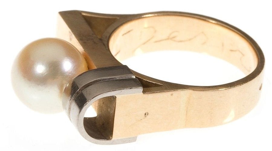 Jean DESPRES (1889-1980)

Bague moderniste en or jaune et or blanc.
La plateforme rectangulaire reçoit une perle et se termine, à une extrémité, par un double arceau.
Signée J. DESPRÉS à la pointe à l'intérieur de l'anneau et porte les poinçons de Maître Orfèvre et de garantie.
Poids: 10,54 g
Provenance:
- Madame D., ancienne propriétaire de l'Hôtel de la Poste et du Lion d'Or à Vézelay (Près d'Avallon ? France), ?uvre acquise directement auprès de l'artiste dans sa boutique d'Avallon.
- Par descendance."
