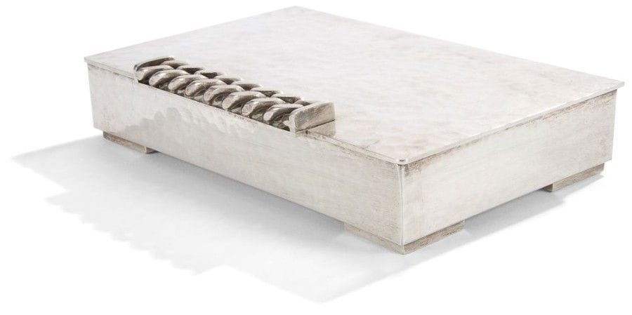 Jean DESPRES (1889-1980)

Coffret à cigares réalisé en métal argenté à surface martelée.
Le corps quadrangulaire repose sur des patins d'angle.
Le dessus présente, à l'intérieur, un jonc en ressaut formant un rectangle et s'ouvre par une prise centrale en débordement formée d'une épaisse gourmette à maillons plats.
Signée J. DESPRÉS sous la base.
3,8 x 20,5 x 13,3 cm
Provenance:
- Madame Yvonne André (1905-1992) à Vézelay, ?uvre acquise directement auprès de l'artiste dans sa boutique d'Avallon.
- Par descendance, Madame Léone Danielle D. (née en 1924), fille de la précédente."
