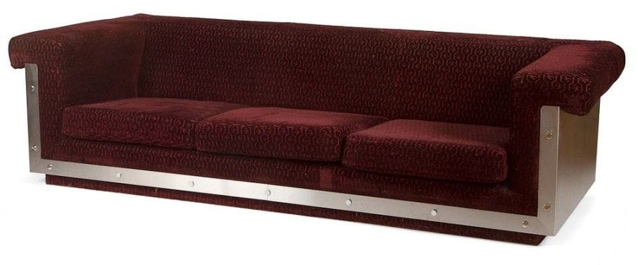 ANNÉES 1970

Grande banquette quadrangulaire sur socle et au dossier en prolongement des accotoirs.
Les flancs, les façades de montant et de ceinture sont parés d'épaisses feuilles d'Inox fixées par des cabochons apparents.
Garnitures et tapisserie d'origine en velours (usagées).
Accidents, manques et état d'usage.
59 x 232 x 90 cm"