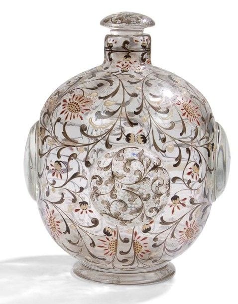 Émile GALLÉ (1846-1904) ? Louis HESTAUX (1858-1919) Collaborateur

Rare flacon sphérique, sur talon, au bouchon bombé.
Épreuve en verre au décor émaillé polychrome de rinceaux et de fleurs sauvages.
La panse est ornée de quatre cabochons collés à chaud, deux présentant un motif de rinceaux sur fond pastillé, les deux autres aux décors d'une danseuse à l'écharpe et d'une Renommée. 
Vers 1889.
Restaurations au talon.
Signé Émile GALLÉ, porte diverses étiquettes ? Cabochons peints par Hestaux 1889 ? HHSSY 350 ? 6762 ? H4 au revers.
Hauteur: 15 cm"