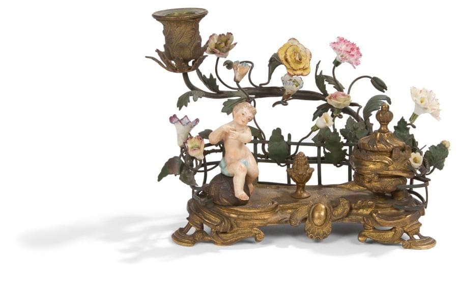 Encrier en porcelaine et bronze doré à un godet et un bras de lumière dans un entourage de fleurs. Style Louis XV (accidents et manques). H.: 16 cm, L.: 17 cm