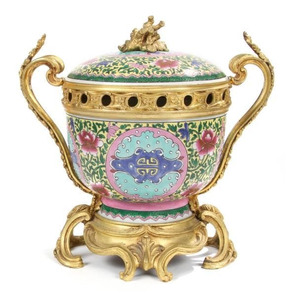 Vase pot-pourri en porcelaine imitant la porcelaine de Chine à monture de bronze doré, les anses ajourées et feuillagées réunies à une base à décor de feuillages et palmettes, le couvercle orné d'un motif de corail. Style Louis XV. H.: 36 cm, L.: 37 cm