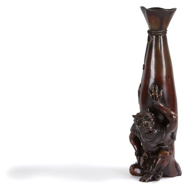 JAPON - Vers 1900

Vase en bronze à patine brune formant un sac à col évasé, noué par un cordon en relief, posé sur le dos d?un oni assis les jambes croisées.
H.: 30,7 cm