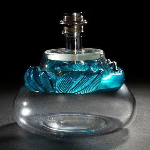 MAISON LALIQUE d'après un modèle de Marie-Claude LALIQUE (1935-2003)

Cyrus
Vase bursaire formant pied de lampe, en cristal soufflé au décor tournant d'un serpentin rainuré en cristal turquoise appliqué à chaud. Complet de son système le transformant en lampe. Signé LALIQUE ® France en lettres cursives à la pointe sous la base. H. totale: 24 cm, sans la douille: 17 cm