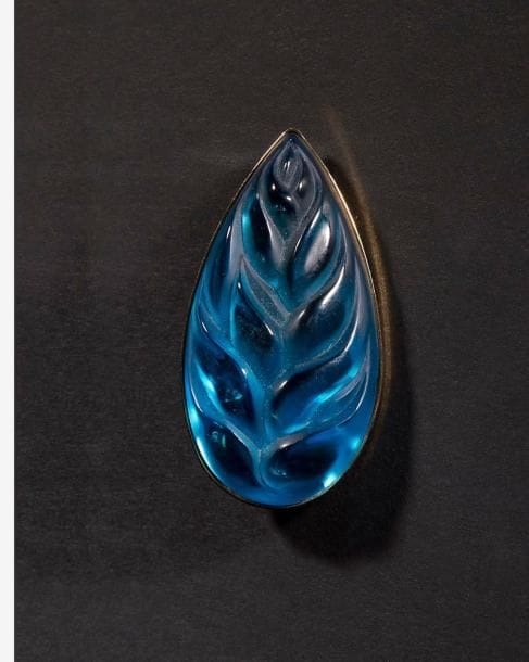 MAISON LALIQUE d'après un modèle de Marie-Claude LALIQUE (1935-2003)

Héliconia
Broche en cristal bleu turquoise sur monture en métal doré. Signée LALIQUE France au revers de la platine. L. 5,5 cm