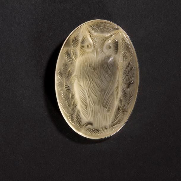 MAISON LALIQUE d'après un modèle de Marie-Claude LALIQUE (1935-2003)

Hibou
Broche en cristal moulé-pressé, achevé satiné, sur tain miroir jaune pâle. Platine en métal argenté. Signée LALIQUE France au revers de la platine. L. 6,5 cm