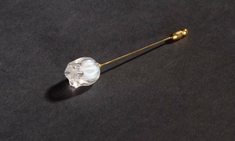Maison LALIQUE

Muguet.
Épingle à foulard ou à chapeau. Verre moulé semi-opalescent et tige en métal doré. Signée LALIQUE en lettres cursives sur la fleur. Longueur totale: 7 cm