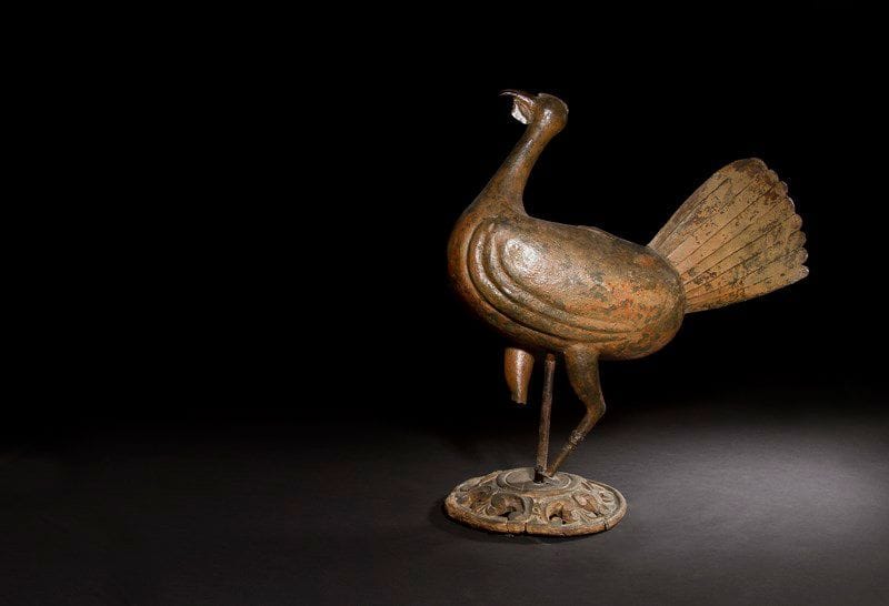 Girouette en tôle patinée reposant sur un socle en bois sculpté et ajouré (rapporté).
XIXe siècle (accidents).
H. 54 cm