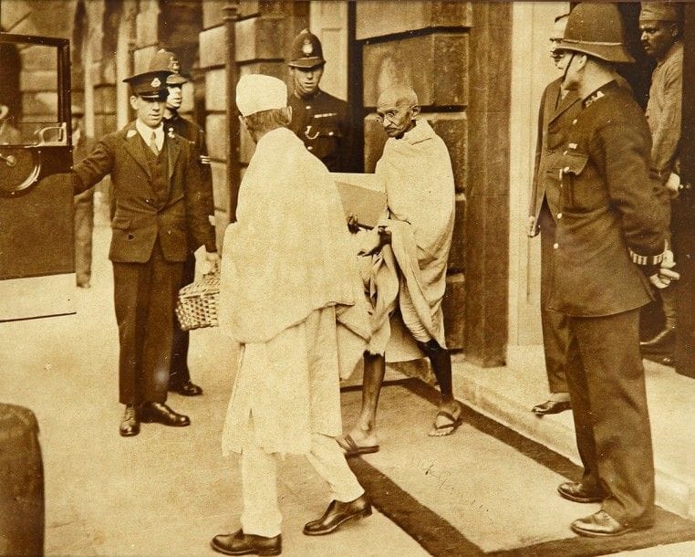 Mohandas Karamchand GANDHI (1869-1948)
Photographie avec signature autographe «MK Gandhi»; 18,4 x 23 cm à vue (encadrée, encre un peu pâle) Photographie de presse originale, avec le cachet au dos de Planet News Ltd. Elle représente Gandhi quittant le palais de Saint-James où il avait assisté à la deuxième Round Table Conference à propos des réformes constitutionnelles en Inde (7 septembre-1er décembre 1931), sous l'oeil des policiers; Gandhi a signé sur le paillasson sur lequel il marche(*)