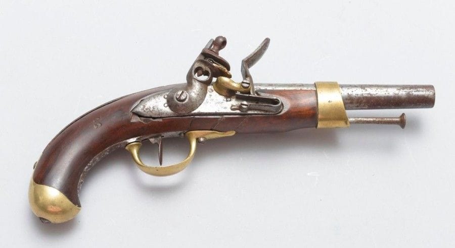Pistolet d'arçon modèle An XIII.
Canon rond à méplat au tonnerre. Platine gravée «Mre Imple?». Garnitures en laiton poinçonné «P» sous couronne. Crosse en noyer matriculée «12». Baguette en fer.
E.M. Oxydation du métal