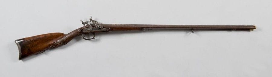 Rare fusil de chasse par «Lepage Arqueer ordinaire du Roi», double, à percussion, mise à feu par boulette de fulminate.
Canons en table en beau damas de couleur tabac, décorés à l'or aux bouches et autour du point de mire de feuillages, signés à l'or «Lepage Arqueer ordinaire du Roi». Point de mire en argent. Platines dites à «flacons de parfum» signées «Lepage Arquebr du Roi à Paris» et chiens à corps plats finement gravés de personnages mythologiques, chiens et loups. Belles garnitures en fer découpé, gravé, ciselé d'urnes, de frises de fleurs, de flambeaux, de feuilles d'acanthe et d'arcs. Crosse à joue, en beau noyer choisi, sculptée d'une tête d'animal fantastique, de frises de feuillages, d'éventails, de feuilles d'eau, de coquilles et en partie quadrillée.
B.E. Daté «1815». Beau et intéressant système de mise à feu
