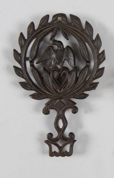 Repose-fer à repasser en fonte de fer noircie, ajouré, motif à l'aigle sur un c?ur entouré d'une couronne de laurier.
B.E. Époque Second Empire