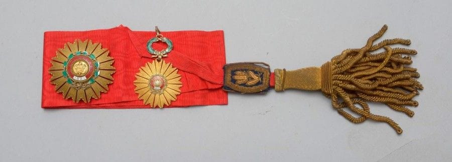 PÉROU 
ORDRE DU SOLEIL, fondé en 1821. 
Ensemble de Grand-Croix comprenant: 
- Un bijou. Bronze doré, couronne en vermeil et émail. 
Hauteur: 9 cm
- Une plaque. Bronze doré, vermeil et émail.
Hauteur: 7,8 cm 
Marque de la Monnaie de Lima. 
On y joint une écharpe en moire écarlate à gland et franges en passementerie or. 
B