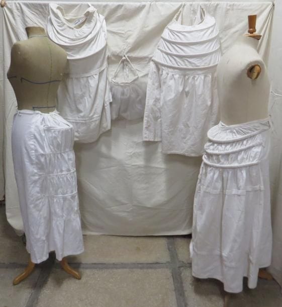 Quatre jupons "faux culs" et un faux cul pour femme, style XVIIIe-XIXe. Matières: coton et synthétique.