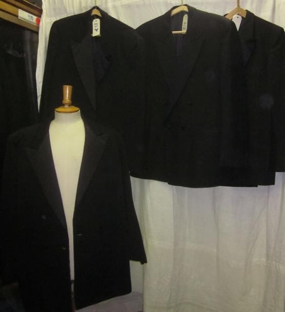Une quinzaine de vestes noires de smoking pour homme de style XXe.