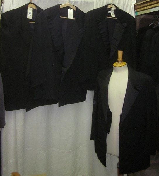 Une quinzaine de vestes noires de smoking pour homme, style XXe.