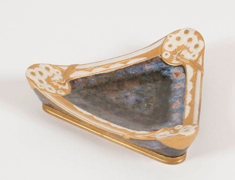 PAUL LOUCHET (1854-1936)
Vide-poche triangulaire en porcelaine émaillée au décor de semis floraux en biscuit rehaussé à l'or mat. Le talon en bronze doré. Circa 1900. Marqué Alp. L - P. L. T sous la base et du cachet circulaire Paul LOUCHET sur le côté. 18 x 18 x 18 cm