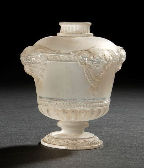 RENE LALIQUE (1860-1945)
Bouquet de faunes, grand modèle, dit aussi Vasque Louis XVI, pour GUERLAIN, au registre des modèles le 7 août 1925 Flacon à parfum. Corps en verre blanc soufflé-moulé (Réf. Marcilhac Guerlain-1 page 940). Manque le bouchon. Marqué GUERLAIN Paris en relief sur l'urne et Made in France sur la tranche du piédouche. Porte le numéro 123 et la lettre H, gravés sous la base. H.: 12 cm