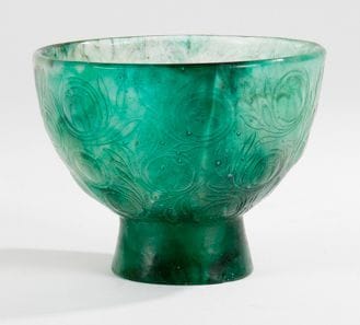FRANÇOIS-ÉMILE DECORCHEMONT (1880-1971)
Bol fruits et feuilles - Modèle 197 créé en 1922 et diffusé jusqu'en 1925 à 15 exemplaires. Bol creux sur talon, épreuve en pâte de verre aux traînées marmoréennes vertes. Un petit éclat à la base. Porte le cachet de l'artiste et la référence A7 gravé sous la base. H.: 9 cm - D.: 11,5 cm (Biblio. « François Decorchemont - maître de la pâte de verre » Véronique Ayroles, Norma éditions, Paris, 2006, modèle référencé et reproduit (exemplaire bleu) sous le n°197 p. 257)