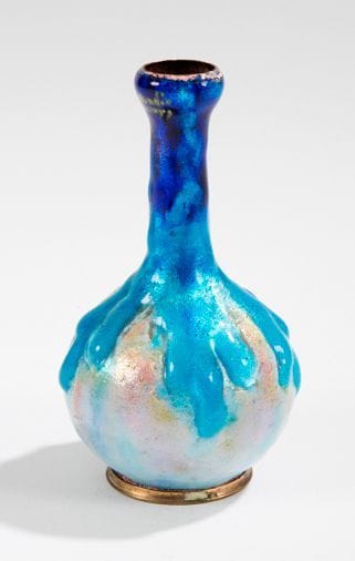 Jules SARLANDIE (1874-1936) Limoges
Petit vase boule sur pied à haut col trompette, en cuivre à décor de coulures d'émaux bleus translucides sur fond d'un paillon argent. Usures d'émail au col. Signé SARLANDIE et situé LIMOGES au col. H.: 10,5 cm