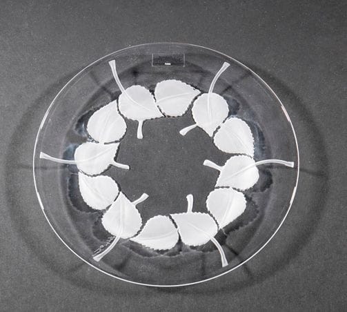 Maison LALIQUE
Rolleboise Assiette en cristal moulé-pressé et, en partie, satiné à décor de feuilles. Vendue dans son coffret d'origine. Signé LALIQUE ® France en lettres cursives sur la pointe sous la base. D.: 19,5 cm