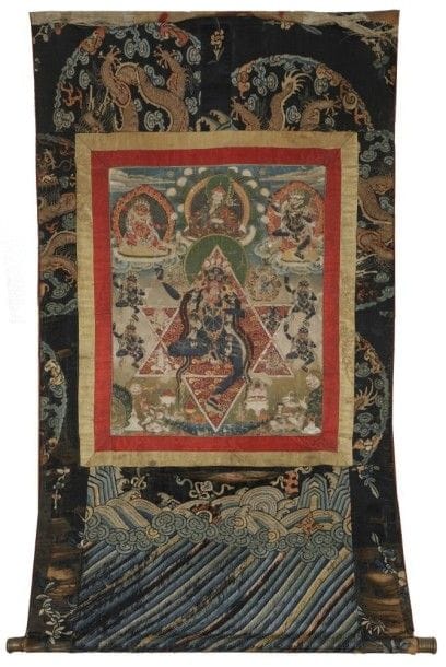 TIBET - XVIIIe siècle

Tangka, détrempe sur toile, vajradakini la noire debout sur une jambe dansant tenant le couperet et buvant dans la coupe de sang (kapala), inscrite entre deux triangles, l'un la pointe en bas l'autre la pointe en haut ,formant une étoile à six pointes appelée «tikonacakraradvaya», «roue en double triangle», symbole du principe féminin et masculin; elle est surmontée de Padmasambhava assis flanqué de deux Mahakala et entourée de quatre dakini dansantes. 
(Traces de pliures). 
Dimensions: 43 x 35 cm