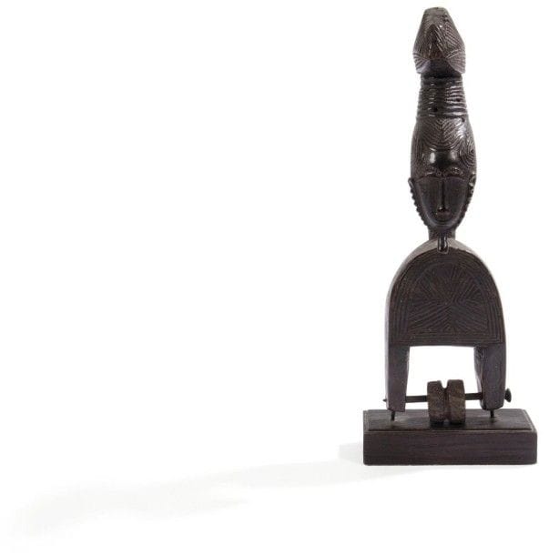 BAOULÉ / YAOURE (R. CÔTE d'IVOIRE)

Poulie de métier à tisser 
Très bel étrier de poulie formé d'une fourche finement décorée de motifs géométriques, surmontée d'une représentation humaine définissant un véritable portrait. Sculptés avec un grand raffinement les traits du visage sont décrits dans un c?ur ceint d'une barbe crénelée. Coiffure trilobée terminée en chignon zoomorphe. Belle patine brun foncé et brun rouge. Bobine en noix enfilée sur un clou. Étiquette collée dans le dos: Morigi, Lugano, N°191. 
Hauteur: 21,5 cm 
Provenance: Collection Paolo Morigi, vente Sotheby's, étiquette Sotheby's, lot n°84. / Collection particulière, Paris. 
Bibliographie: pour des poulies de même type cf vente collection Vérité, Drouot, Paris, 2006, p. 93, 123 et 443.
