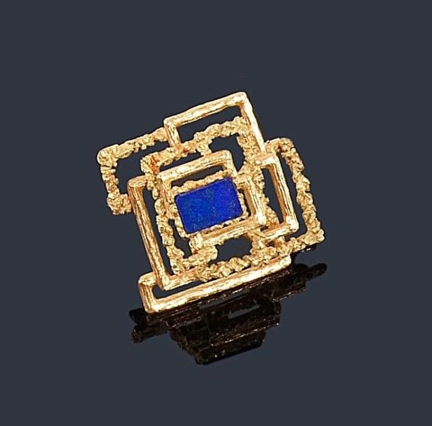 Broche ajourée en or jaune 18K (750 ?) «sauvage» formant un motif géométrique, ornée d'un lapis lazuli de forme rectangulaire. Travail français, vers 1970. 
Dimensions: 3,5 x 3,5 cm environ. Poids brut: 16,4 g