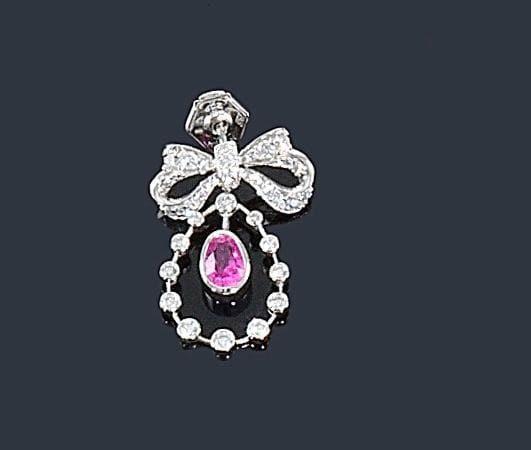 MELLERIO dits MELLER
Broche noeud d'or gris 18K (750 ?) serti de diamants retenant en pampille un saphir rose de forme ovale. Signée et numérotée 5820. 
Hauteur: 2,5 cm environ. Poids brut: 4,3 g