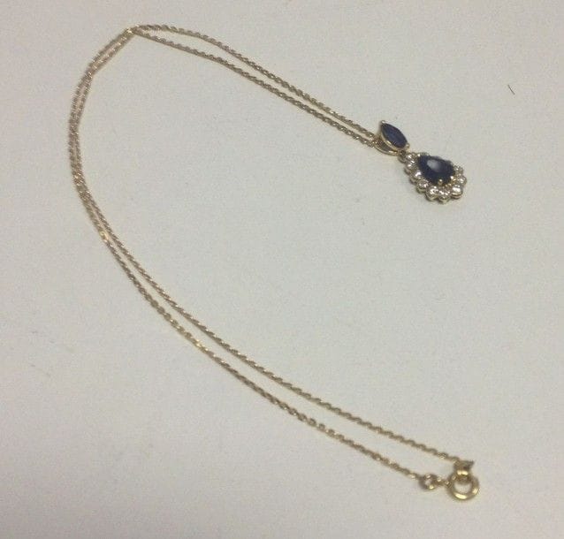 Collier en or jaune 18K (750 ?), orné d'un pendentif en or 18K (750 ?) orné de saphirs et de diamants. 
Poids brut: 3,9 g