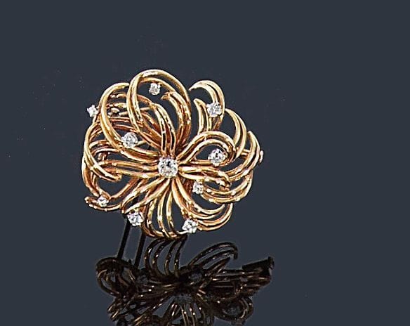 BOUCHERON (monture)
Broche-clip en fils d'or jaune 18K (750 ?) représentant une fleur stylisée, piquée de diamants. Signée monture Boucheron. Dans son écrin. 
Dimensions: 3,7 x 3,5 cm environ. Poids brut: 17,5 g
