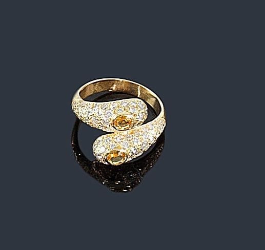 Bague croisée en or jaune 18K (750 ?), ornée de 2 saphirs jaunes dans des diamants pavés. 
Tour de doigt: 55. Poids brut: 5 g