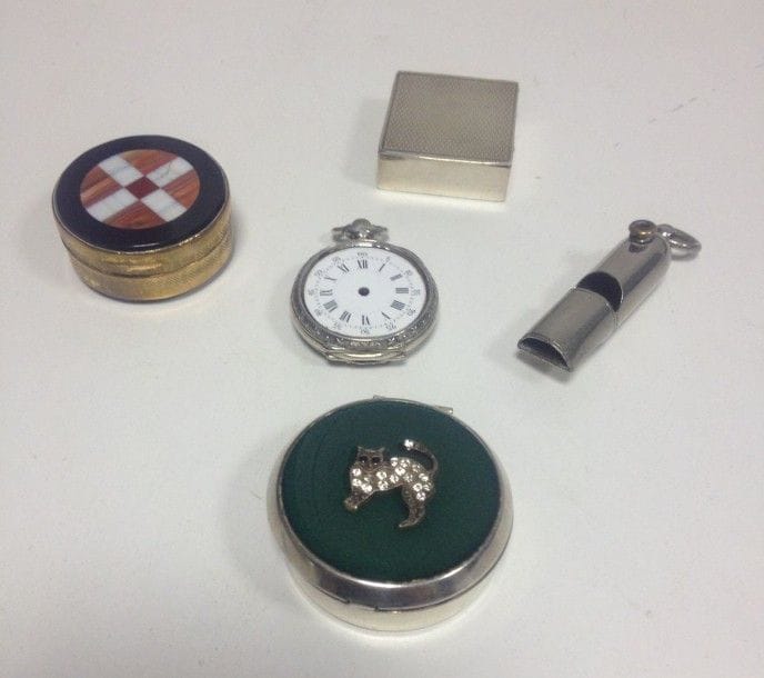 Quatre piluliers dont deux en argent et deux en métal et une montre. On y joint un sifflet en métal.
Poids brut: 64,10 g