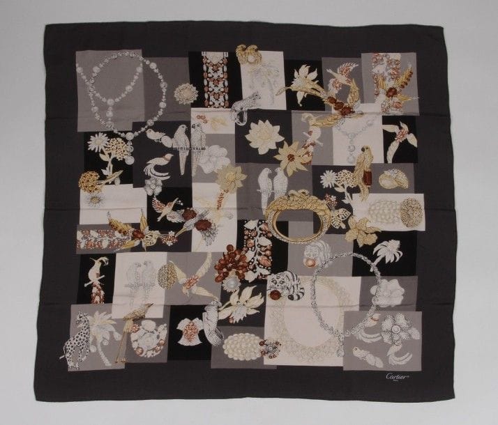 Un foulard CARTIER en crêpe de soie à décor de bijoux et oiseaux. 
Dans sa boîte.