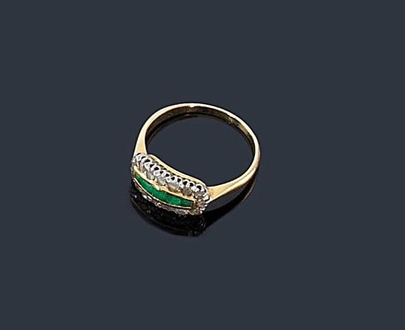 Bague en or jaune 18K (750 ?), ornée d'une ligne d'émeraudes entre deux lignes de diamants taillés en roses. 
Tour de doigt: 55. Poids brut: 2,8 g