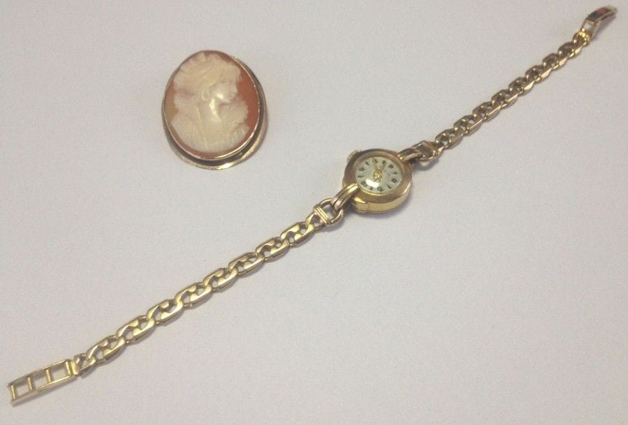 Montre de dame en or jaune 18K (750 ?), cadran rond, bracelet chaînette d'or jaune 18K (750 ?). Poids brut: 16 g
On joint une broche en or jaune 14K (585 ?) ornée d'un camée coquille ciselé d'un portrait de femme de profil. 
Poids brut: 4,6 g