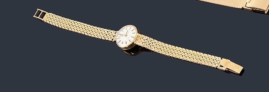OMEGA
Montre de dame en or jaune 18K (750 ?), cadran rond, fond satiné, index bâtons, bracelet ruban souple en or, mouvement mécanique. 
Longueur: 16,5 cm environ. Poids brut: 21,8 g (remontoir à replacer)