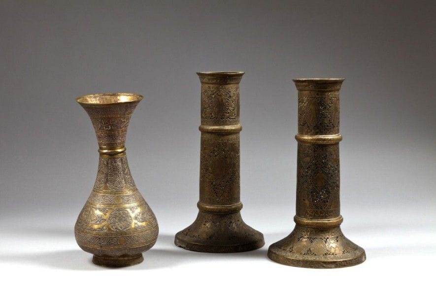 Paire de flambeaux et vase balustre en laiton, Iran et Moyen - Orient, début XXe siècle
Flambeaux cylindriques à décor ajouré de médaillons et de personnages entre deux bourrelets; vase balustre à décor d'épigraphie incrusté d'argent.
Haut.: bougeoirs: 29 cm; vase: 26,5 cm.
État: petits accidents.
A pair of brass and a baluster vase, Iran and Near East, early 20th century
