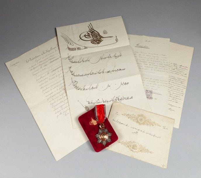 Firman de Mehmet V (1909 - 1918)

Nommant Jules Sauvaire vice - consul de Turquie, le 24 mai 1901, et accordant le nishan de l'ordre du Medjidi, 4e classe.
Ensemble comprenant le firman de la tughra de Mehmet V daté le: 19 du mois de Rabi al - Aval 1322 H./1904; sa traduction par le consul général de Turquie à Marseille le 14/27 juillet 1911; une autre traduction anonyme, et l'accord du Président de la République française pour la nomination de Jules Sauvaire, signé Émile Loubet (1899 - 1906) et son ministre des affaires étrangères Théophile Delcassé; une enveloppe ornée de la médaille de l'ordre de Medjidi et la médaille dans son présentoir en velours estampé de la tughra de Mehmet V. Médaille étoilée à l'ordre de Medjidi (datée 1268 H./1852) en argent en pointe de diamants à centre et bélière en or émaillé rouge présentant sur une face la tughra, entourée de la devise de l'ordre (probité, zèle et ardeur). Au revers, centre convexe estampé du nom du fabricant «Zar'rab Khaneh Ali Murad».
Dim.: 8,5 x 5,7 cm.
An Ottoman silver and enameled Medjidi Order 4th class breast badge with a Firman of Sultan Mehmet V (r. 1909 - 1918)
